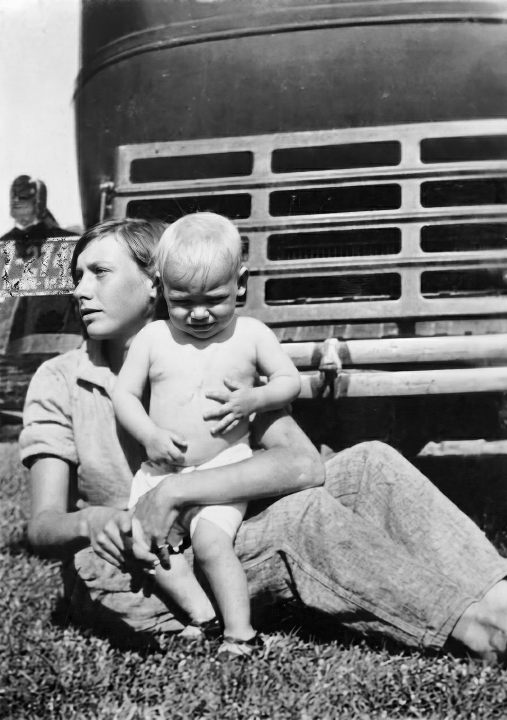 Norma as a teenager holding her baby brother on the grass